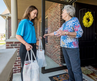 woman receiving groceries from helper